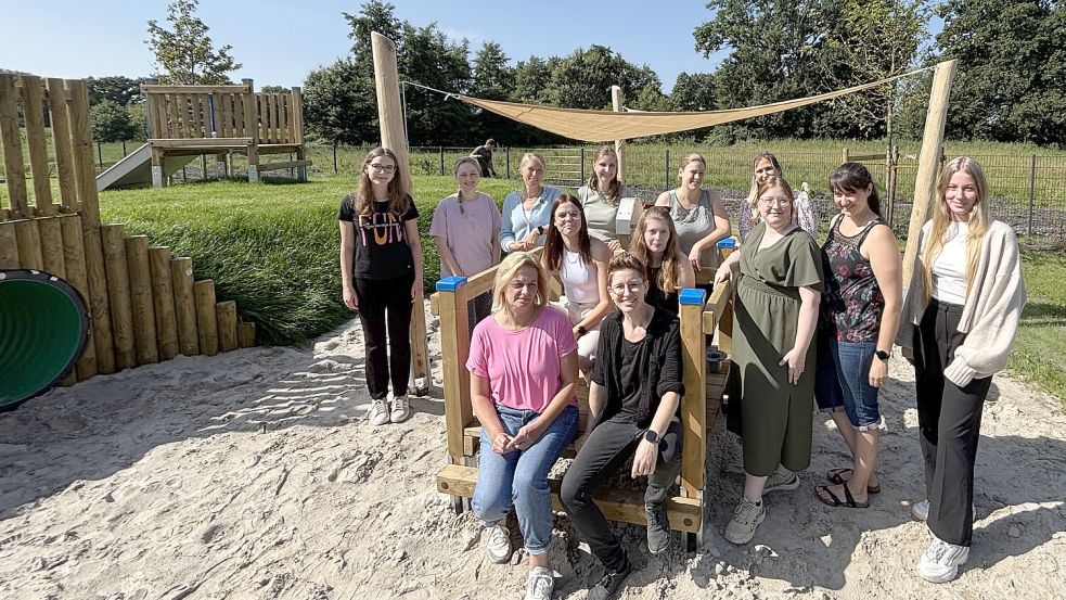 Kindergartenleiterin Imke Hackmann (hinten, 3. von links) und ihr Team auf dem großen Spielgelände des neuen Kindergartens. Alle freuen sich, dass es hier los gehen kann. Foto: Marion Janßen