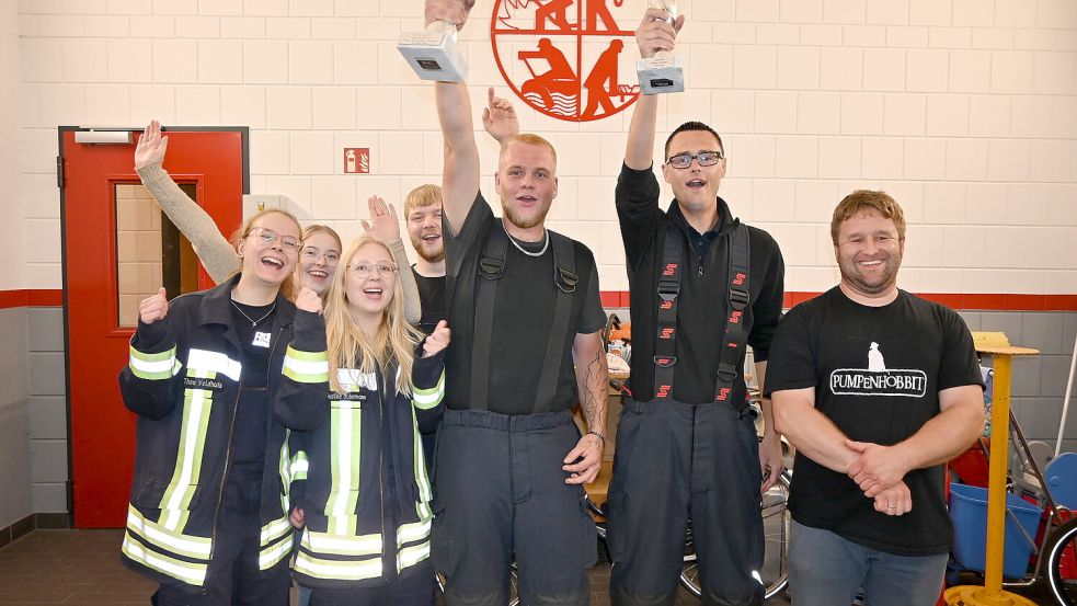 Stolz reckt die Wettkampfgruppe der Freiwilligen Feuerwehr Collinghorst den Wanderpokal (links) und Siegerpokal (rechts) in die Höhe. Fotos: Holger Weers