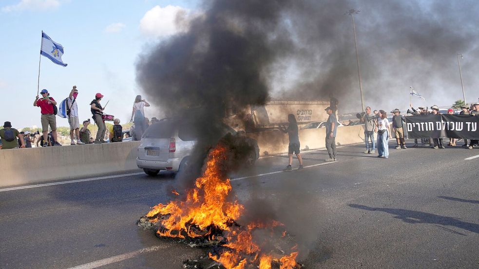 Israelische Demonstranten blockieren eine Straße bei einem Protest. Foto: Ohad Zwigenberg/AP/dpa
