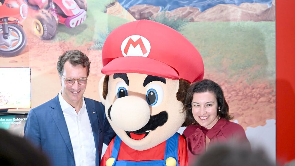 Beim Messerundgang über die Gamescom kam der Tross von Politikern auch beim Messestand von Nintendo vorbei, hier stehen NRW-Ministerpräsident Hendrik Wüst (CDU) und Bundesforschungsministerin Dorothee Bär (CSU) neben einer Mario-Plüschfigur. Foto: Wolf von Dewitz/dpa