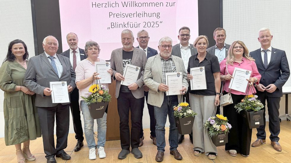Die Ausgezeichneten des Blinkfüür 2025 mit den Laudatoren Matthias Groote (rechts) und Gitta Connemann (links), Bürgermeistern oder Stellvertretern sowie Sparkassen-Vorstand: Bernhard Robbers (vordere Reihe, ab Zweitem von links), Helga Frerichs, Werner Lambertus Stalljann, Gerhard Willms, Brigitt Hejnal-Modder und Ana-Maria Andrei. Es fehlt Werner Müller. Foto: Jonas Bothe