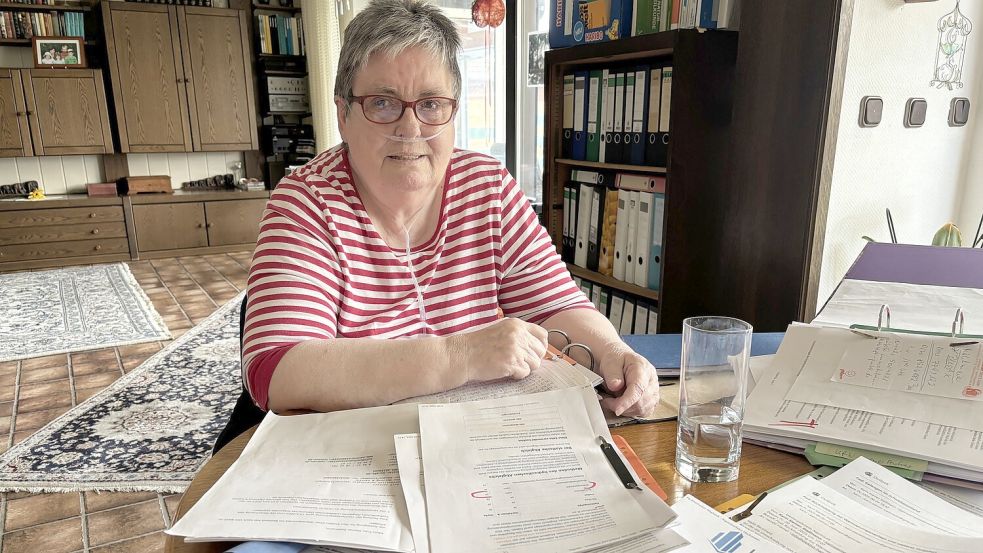 Karin Siemer-Stallmann sitzt vor einem Stapel Unterlagen, die sich im Zusammenhang mit dem Kauf der Wärmepumpe angesammelt haben. Foto: Horst Kruse