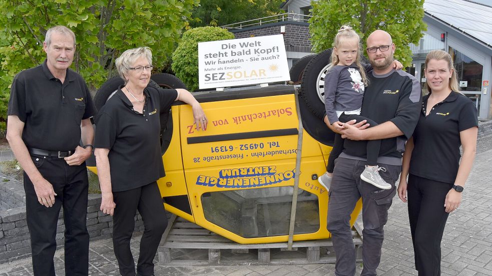 Am Eingang zum Betriebsgelände liegt ein E-Auto auf dem Dach: „Die Welt steht bald Kopf. Wir handeln - Sie auch?“ steht auf einem Schild. Gerwin und Ilona Schulte (von links) haben das SEZ 1985 gegründet. Sohn Tim (mit Tochter Fiona) und Angelina sind vor einigen Jahren in die Firma eingestiegen. Foto: Prins