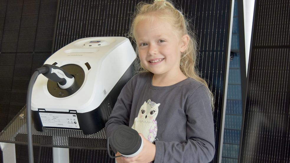 Fiona, Enkeltochter der Firmengründer, steht an einem modernen E-Charger. Das Kabel, das sie hält, wird an ein E-Auto angeschlossen - und dann kann (vorzugsweise) Solarstrom getankt werden. Foto: Prins