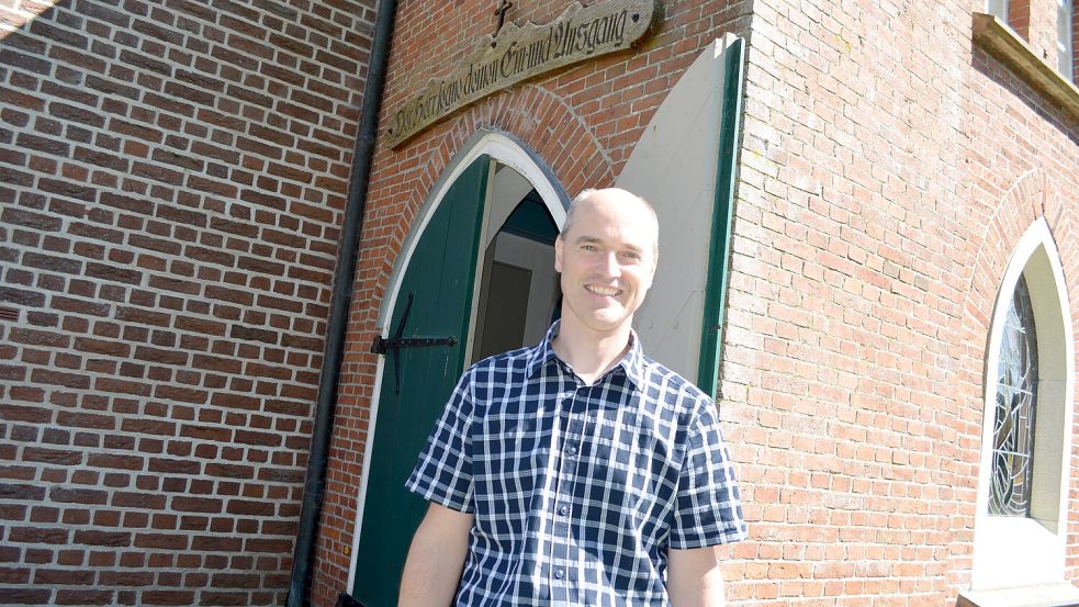 Pastor Matthias Bokelmann freut sich auf seine Amtseinführung. Diese erfolgt am Sonntag, 31. August, in der Rhauder Kirche, vor deren Eingang der 44-Jährige hier steht. Foto: Astrid Fertig