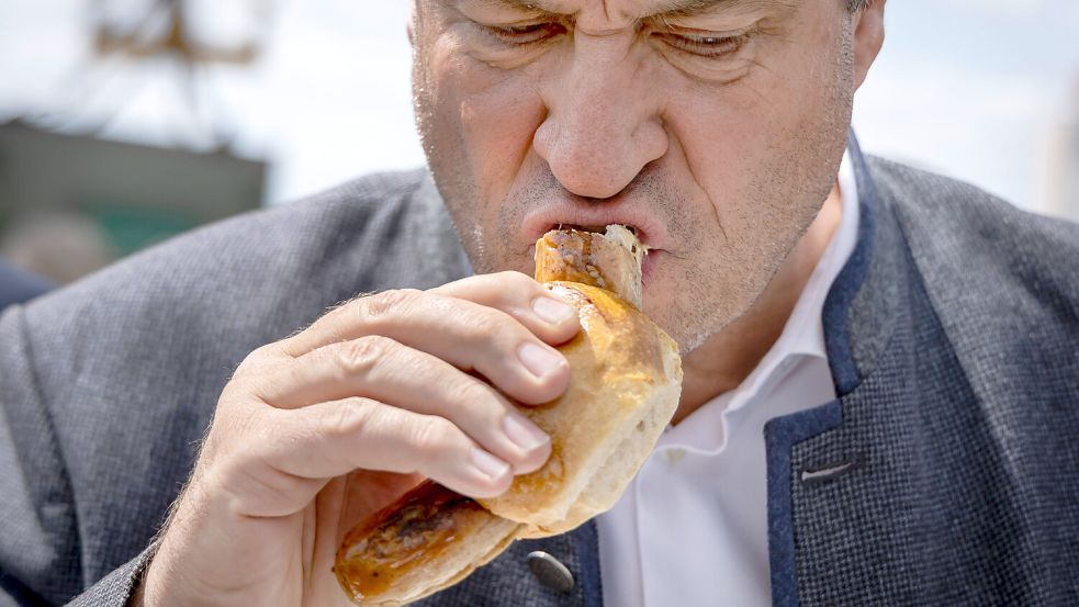 Der bayerische Ministerpräsident Markus Söder (CSU) isst nicht einfach nur die Wurst, er merzt sie regelrecht aus. Foto: IMAGO/Uwe Meinhold