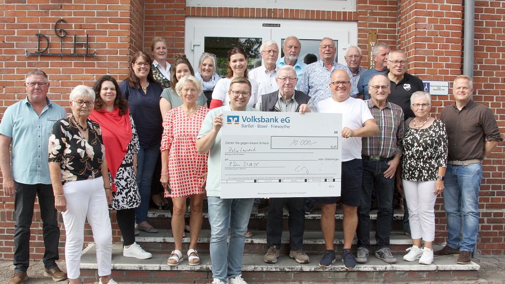 Claas Meyer (vordere Reihe, 4. von rechts), der Veranstalter des Riesenflohmarktes entlang des Elisabethfehnkanals, konnte jetzt im Dorfgemeinschaftshaus in Elisabethfehn einen Spendenscheck in Höhe von 10.000 Euro an Dieter Prahm (Mitte), dem Sprecher des Flohmarktgremiums, überreichen. An der Scheckübergabe nahmen auch Barßels Bürgermeister Nils Anhuth (links am Scheck) sowie Mitglieder des Flohmarktgremiums und der Vereine teil. Foto: Hans Passmann