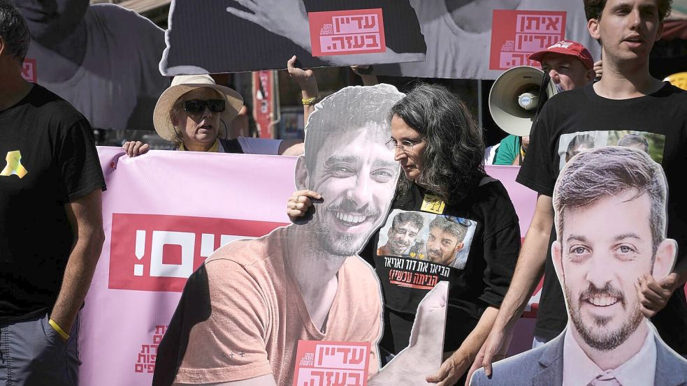 Demonstranten halten bei einem Protest gegen die Offensive in der Stadt Gaza Fotos von Geiseln. Foto: Mahmoud Illean/AP/dpa