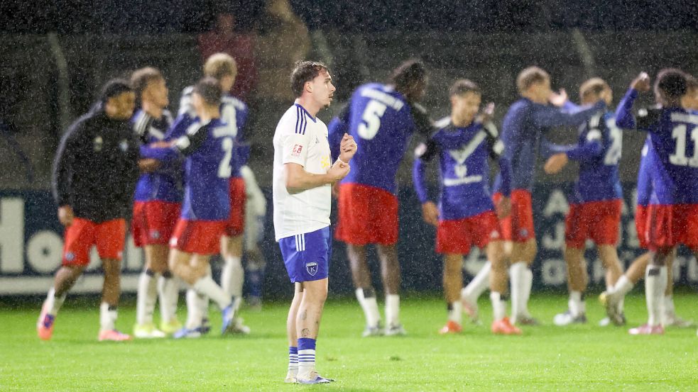 Emdens Michel Eickschläger ist nach dem Schlusspfiff enttäuscht, die HSV-Akteure feiern im Hintergrund. Foto: Jens Doden/Emden