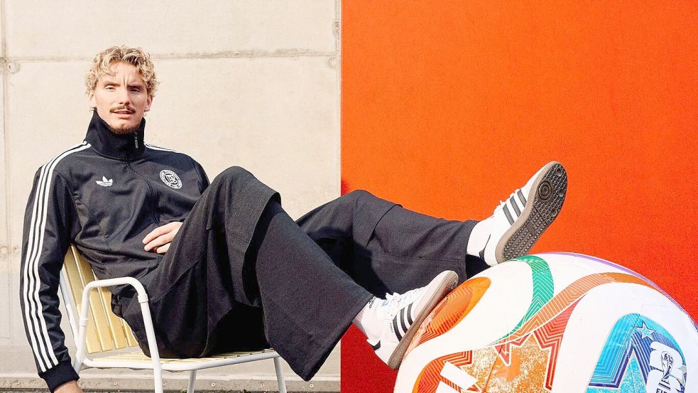 Woltemade posiert lässig mit dem übergroßen Modell des WM-Balls. Foto: ---/Adidas/dpa