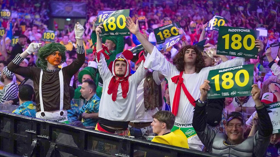 Wie bei der Darts-Weltmeisterschaft im Londoner „Ally-Pally“ können sich die Besucher beim Party-Darts-Event des SV Hellern kreativ verkleiden und feiern. In der Helleraner Sporthalle dürfen sie aber sogar selbst auf die Dartsscheibe werfen. Foto: IMAGO/Every Second Media