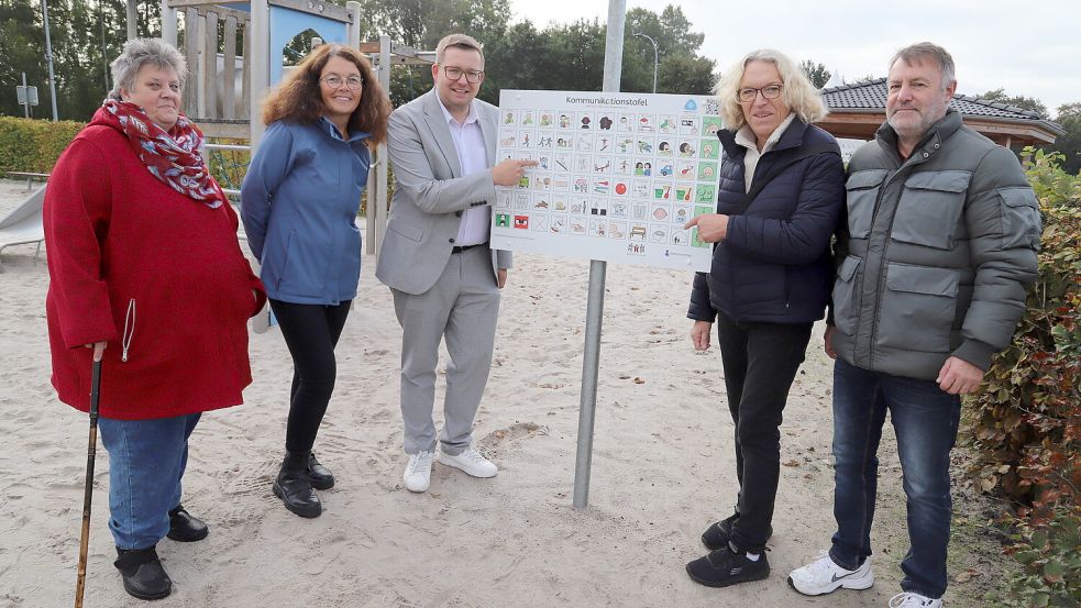 Die Mitglieder des Beirates für Menschen mit Behinderung oder Einschränkung der Gemeinde Barßel (von links) Irene Fuhrich, Liane Rolfsen und Bürgermeister Nils Anhuth sowie (von rechts) Dieter Funke und Karin Schierhorn präsentieren die neue Kommunikationstafel auf dem Traumspielpark. Foto: Hans Passmann