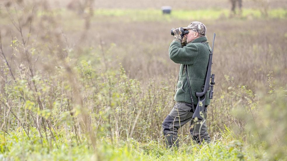 Ein Jäger beobachtet mit einem Fernglas sein Revier. Der Wolf gilt offiziell nicht mehr als gefährdetes Tier. Foto: IMAGO / Agentur 54 Grad