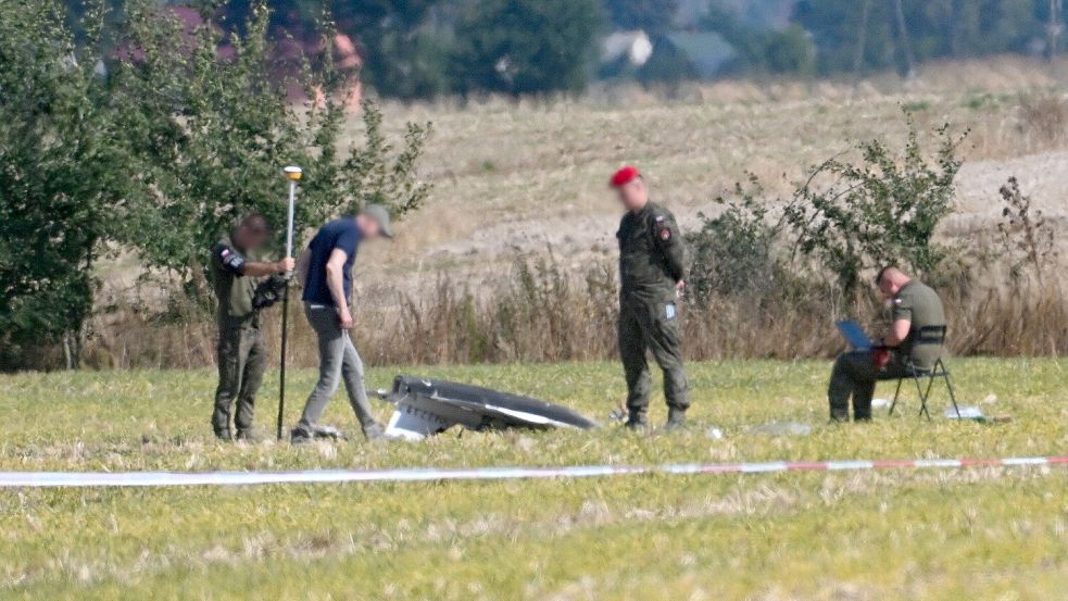 Polizei und Militärpolizei sichern Teile einer beschädigten Drohne, die von polnischen Behörden abgeschossen wurde, auf einem Gelände in Wohyn. Foto: dpa/Wojtek Jargilo