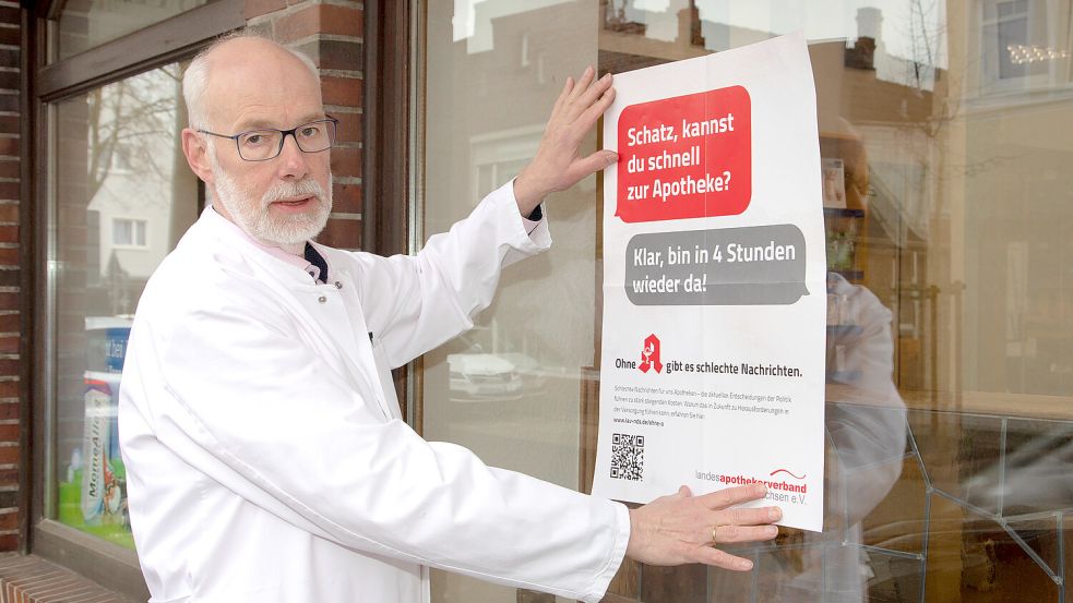 Berend Groeneveld, Vorsitzender des Landesapothekerverbandes, hängt an seiner Rats-Apotheke in Norden ein Plakat auf. Mit den markigen Sprüchen machte der Verband schon 2023 auf die schwierige Situation der Apotheken aufmerksam. Foto: LAV/Fotostudio Ekkenga