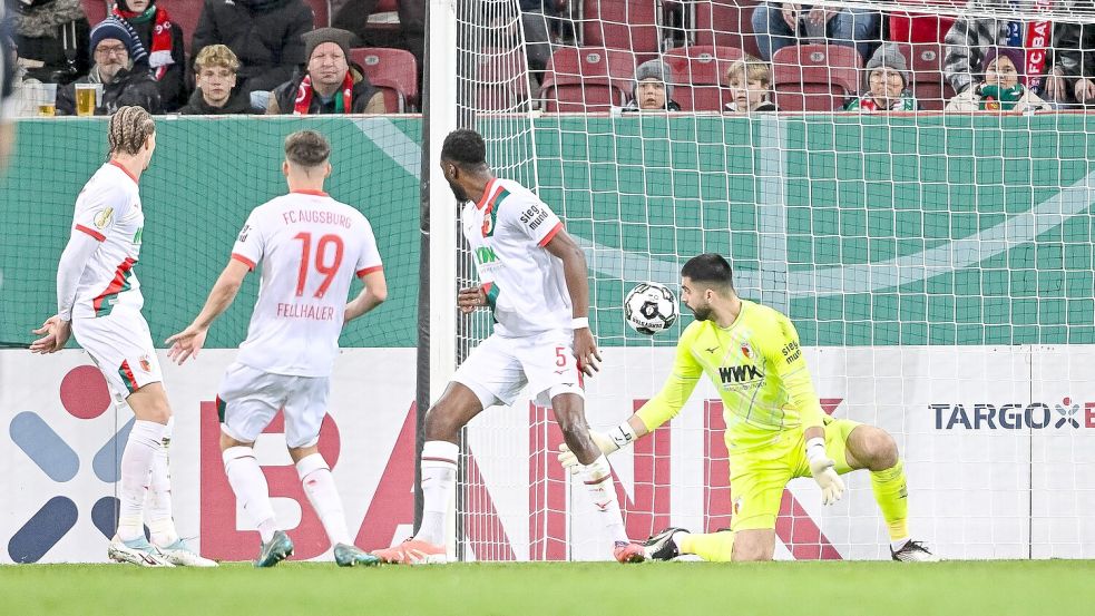 Der Schuss, der zum Augsburger Pokal-K.o. führt. Verteidiger Chrislain Matsima (M) fälscht den Ball auch noch unglücklich und damit unhaltbar ab. Foto: Harry Langer