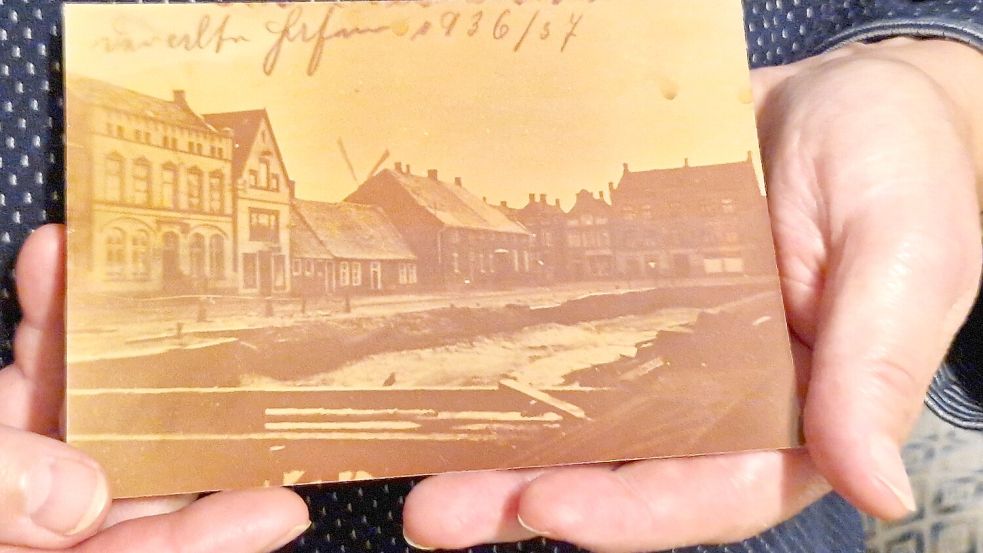 Elisabeth Röttger zeigt ein Foto aus ihrer Fotosammlung. Als das Bild 1936/37 aufgenommen wurde, reichte das Hafenbecken noch bis weit an die Norderstraße heran. Foto: Tatjana Gettkowski
