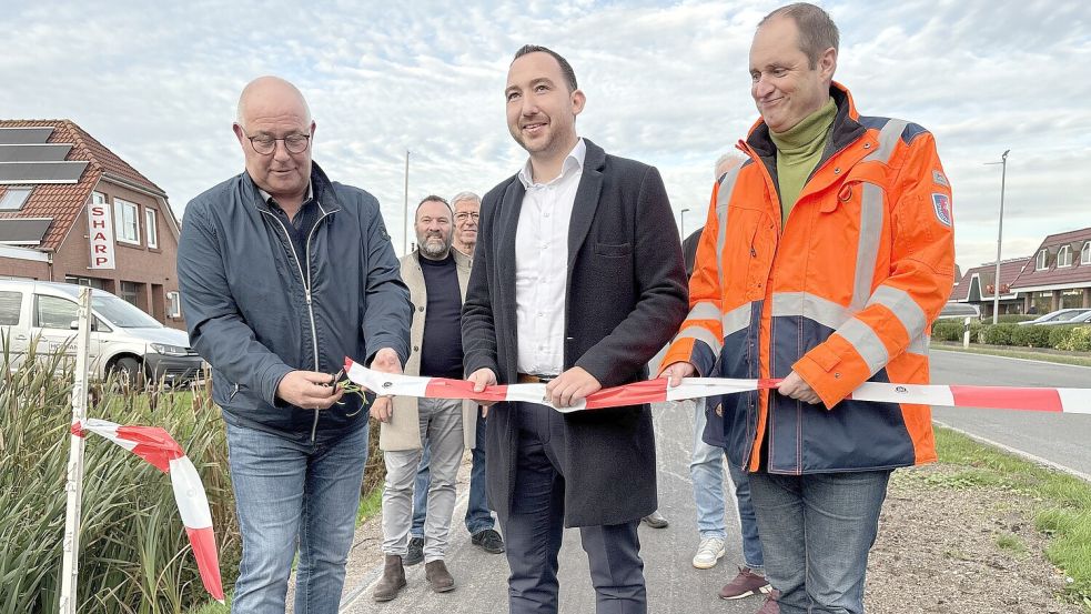 Bürgermeister Hans-Peter Heikens (von links) durchtrennte mit Unterstützung des SPD-Landtagsabgeordneten Nico Bloem und Behördenleiter Frank Buchholz das Flatterband. Foto: Oliver Bär