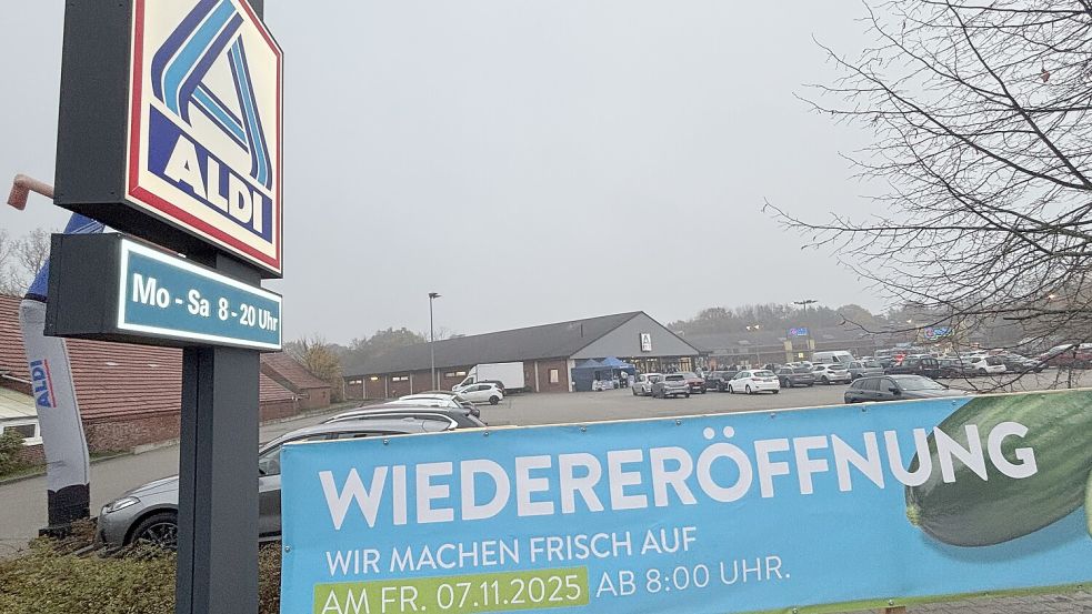 Mit einem großen Banner wird darauf hingewiesen, dass die Aldi-Filiale in Ihrhove (im Hintergrund) an diesem Freitag, 7. November 2025, wiedereröffnet worden ist. Der Markt war für Umbaumaßnahmen rund zwei Monate lang geschlossen gewesen. Foto: Carsten Ammermann