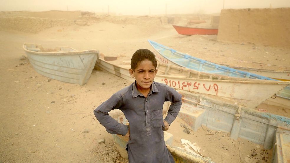 Ein Junge im Iran steht vor alten Booten, wo einst ein See war. Foto: Mohammad Dehdast