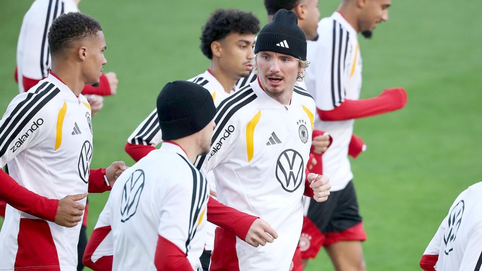 Thiaw (l.) und Woltemade (mit Mütze in der Mitte) laufen beim DFB-Training. Foto: Christian Charisius