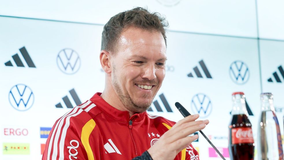 Julian Nagelsmann richtet das Mikrofon bei der Pressekonferenz. Foto: Christian Charisius
