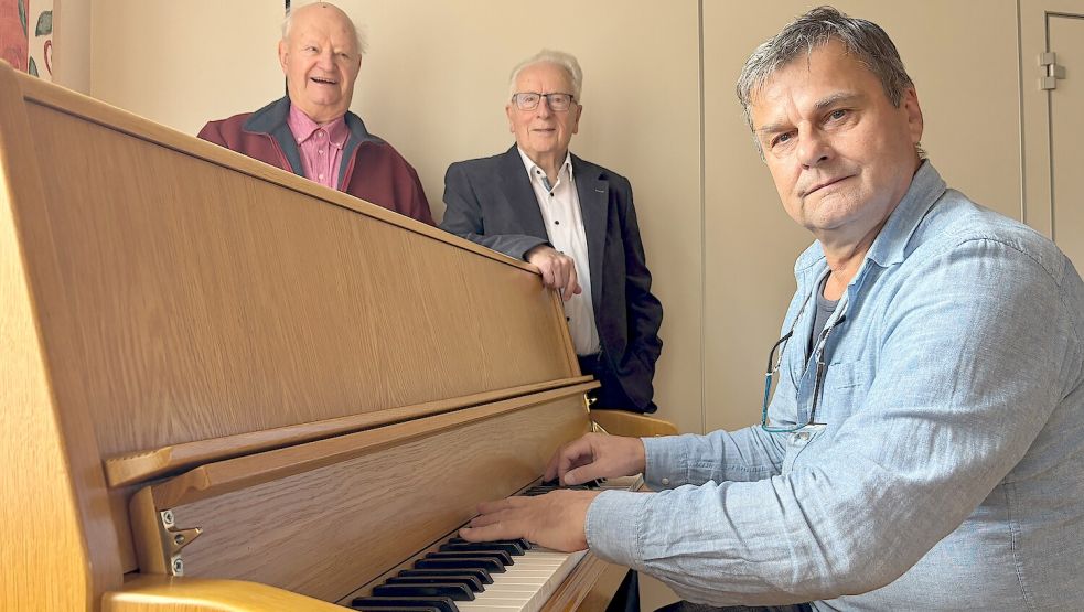 Christoph Bienkowski (von rechts), studierter Musiker und Konzertpianist aus Flachsmeer, sowie Helmut Collmann und Karl-Heinz Jesionek, beide Mitglieder der Arbeitsgemeinschaft „300 Jahre Flachsmeer“, laden für den 29. November 2025 zu einem Konzert unter dem Motto „Vorweihnachtliche Musik - Lieder zum Mitsingen“ ein. Foto: Carsten Ammermann