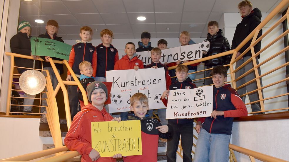 Kinder und Jugendliche von hiesigen Sportvereinen hielten im Rhauderfehner Rathaus Plakate in die Luft, auf denen sie die Errichtung eines Kunstrasenplatzes forderten. Foto: Henrik Zein