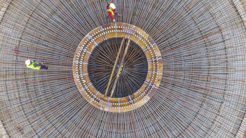 Zwei Arbeiter stehen auf einem Stahlgeflecht für das Fundament einer Windenergieanlage nahe Sieversdorf (Brandenburg). Auch auf dem ATP-Prüfgelände in Papenburg sind nach Angaben der Stadt nun die ersten Fundamente für den Mercedes-Windpark in Papenburg gegossen worden. Symbolfoto: Patrick Pleul