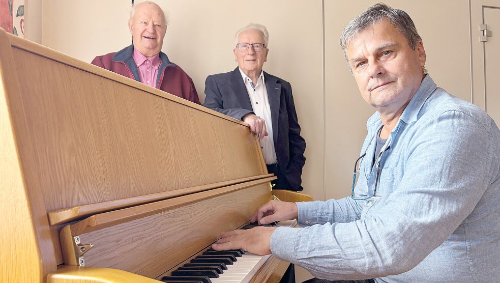 Christoph Bienkowski (von rechts), studierter Musiker und Konzertpianist aus Flachsmeer, sowie Helmut Collmann und Karl-Heinz Jesionek, beide Mitglieder der Arbeitsgemeinschaft „300 Jahre Flachsmeer“, laden für den 29. November 2025 zu einem Konzert unter dem Motto „Vorweihnachtliche Musik - Lieder zum Mitsingen“ ein. Foto: Carsten Ammermann