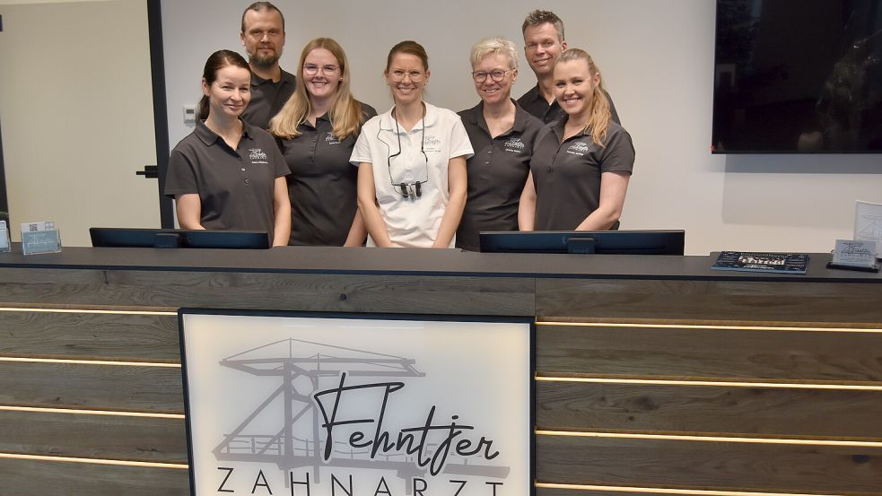Gruppenbild am Empfangstresen: Katrin Hillebrand, Eduard Deisinger, Lena Pruin, Wiebke Würdemann-Arndt, Christa Wehry, Ingo Arndt und Beatrice Schliep bilden das Team der Praxis „Fehntjer Zahnarzt“. Foto: Prins