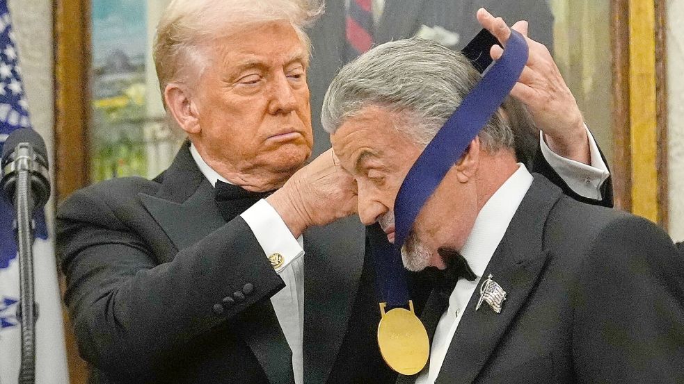 US-Präsident Donald Trump hängt der Actionfilm-Ikone Sylvester Stallone eine Medaille um. Foto: Julia Demaree Nikhinson/AP/dpa