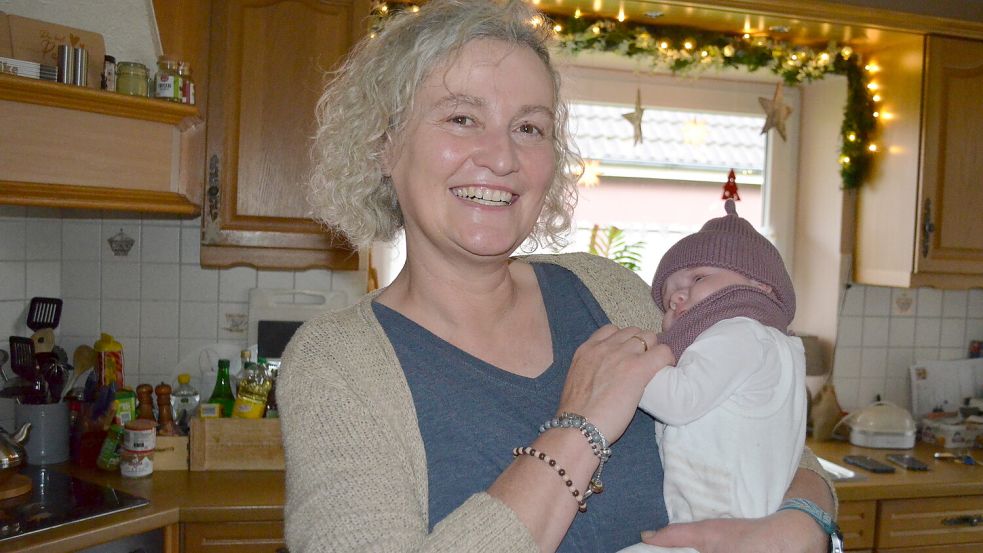Glücklich hält Heike Goldsweer ihre Enkeltochter Hilke auf dem Arm. Zehn Wochen alt ist die Kleine jetzt. Für Hilke wird die Weihnachtstanne im Vorgarten auch im kommenden Jahr noch einmal mit Lichterketten geschmückt. Aber jetzt und auch im Advent 2026 freut sich außerdem die ganze Nachbarschaft daran und alle, die den Rajen in Rhauderfehn entlangkommen. Foto: Astrid Fertig