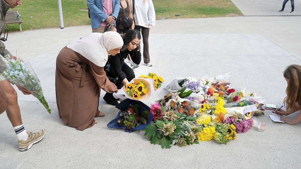 Zahlreiche Menschen legen am Tatort Blumen nieder. Foto: Mark Baker/AAP/dpa