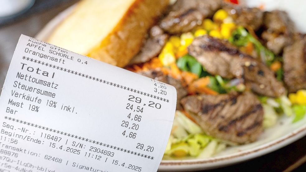 Eine Rechnung mit Mehrwertsteuer neben einem vollen Teller in einem Restaurant. Foto: Sina Schuldt/dpa
