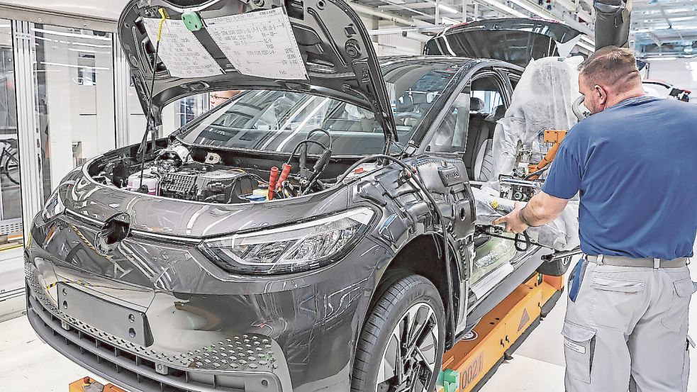 Arbeit in der Industrie: Ein Mitarbeiter in der Automobilproduktion von Volkswagen montiert einen Fahrersitz in ein Elektrofahrzeug. Foto: dpa/Jan Woitas