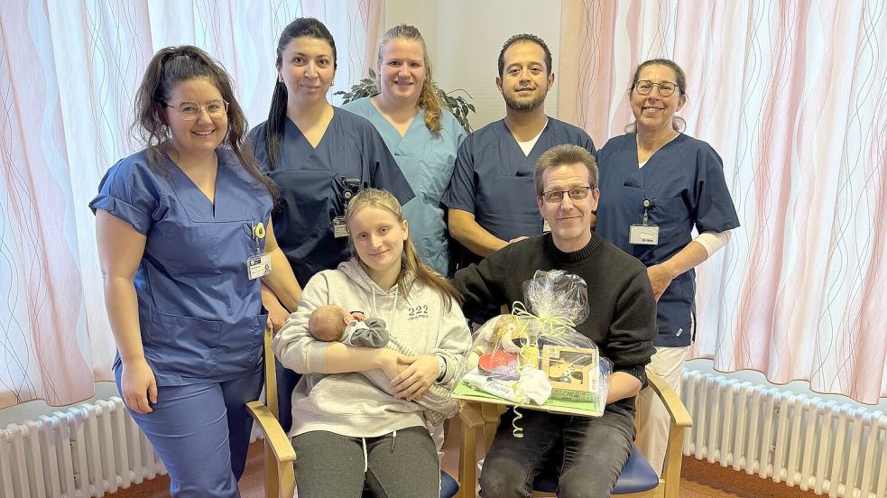 Sie gratulieren: Rhiannon Margolis (Hebamme, von links), Günel Mammadzada (Oberärztin), Jessica Schilling (Gesundheits- und Kinderkrankenpflegerin), Ernesto Giron Garcia (Oberarzt), Sabine Kellner (Oberärztin). Vorne sitzen die Eltern Jessica und Paul Fesenfeld mit Neujahrsbaby Thamara Mila Skyda. Foto: Klinikum Leer