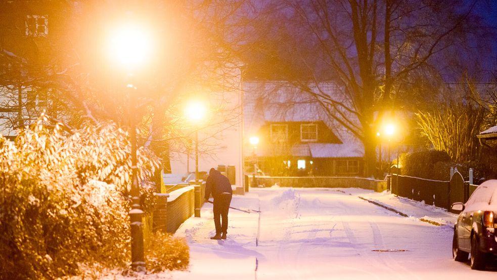 Ein Mann fegt Schnee. Foto: Julian Stratenschulte/dpa