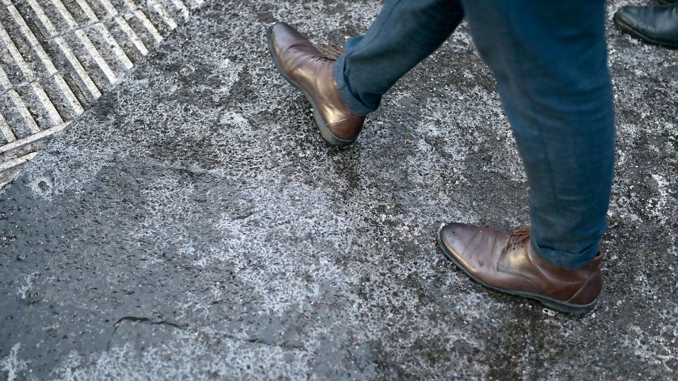 Ein Mann geht über einen vereisten Gehweg. In der Nacht hat es gefrierenden Regen gegeben. Foto: Sebastian Gollnow/dpa