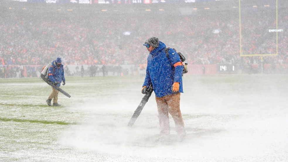 Helfer versuchten die Markierungslinien vom Schnee freizuhalten. Foto: Ashley Landis/AP/dpa