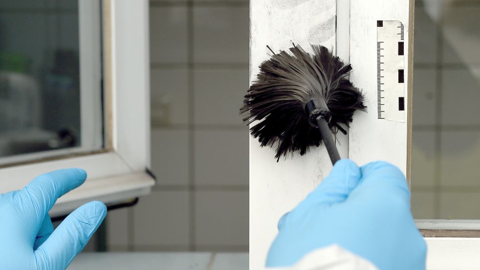 Ein Polizeibeamter demonstriert, wie nach einem Einbruch Spuren aufgenommen werden. Foto: DPA