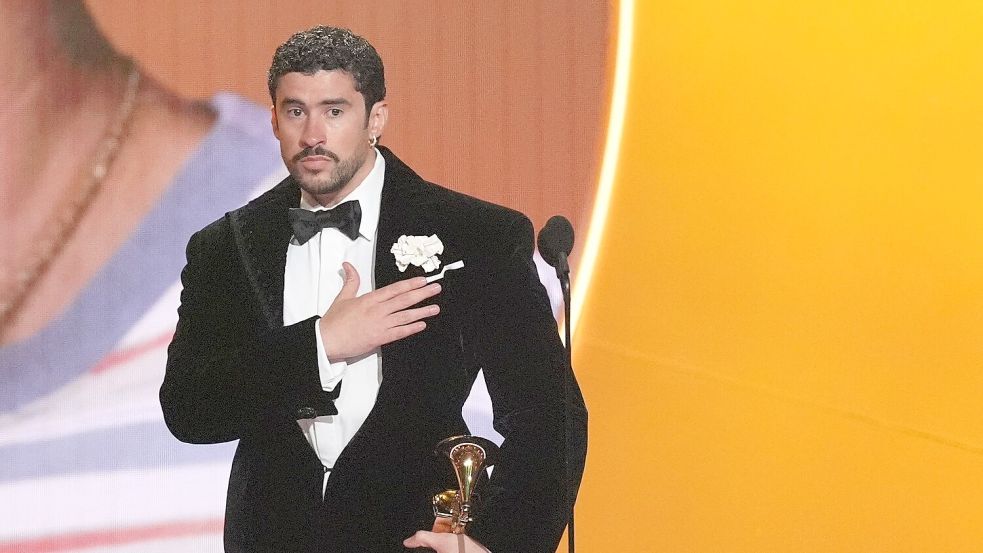 Bad Bunny nimmt den Preis für das Album des Jahres für „DeBÍ TiRAR MáS FOToS“ bei den Grammy Awards entgegen ‒ und zeigt dabei, wo seine Heimat Puerto Rico liegt. (Archivbild) Foto: Chris Pizzello/Invision/AP/dpa