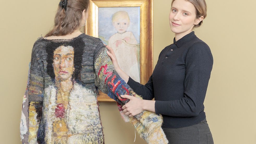 Die Schauspielerin Katharina Stark spielt Paula Modersohn-Becker in einem neuen Film, die Künstlerin Sybille Springer zeigt auf ihrem Kleid Bilder der Künstlerin: Beide posieren im Worspeder Barkenhoff vor dem Gemälde „Mieke Vogeler mit Perlenkette”. Foto: Worpsweder Museumsverbund / Jörg Saerbach