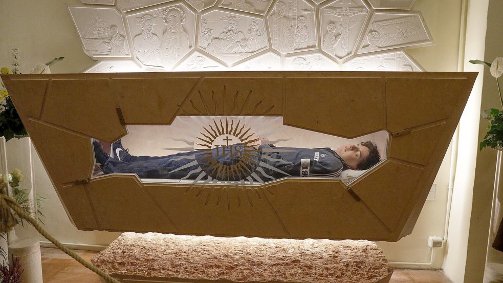 Der Leichnam von Carlo Acutis liegt in einem Sarkopharg, in den man hineinsehen kann. (Archivbild) Foto: Gregorio Borgia/AP/dpa