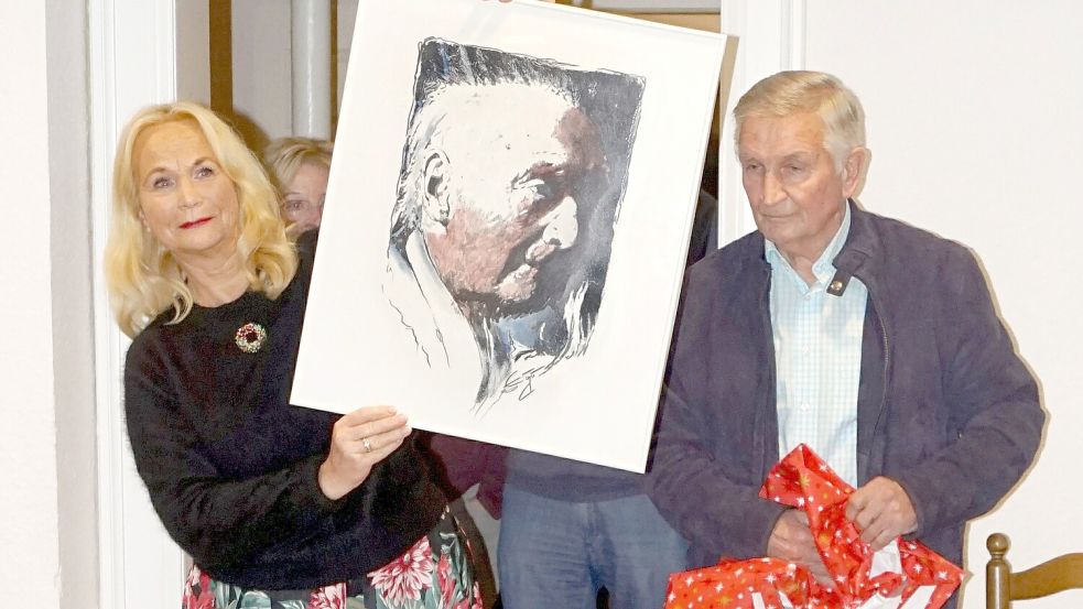 Die Vorsitzende des Heimatvereins Overledingerland, Jutta Kramer, nimmt von Johann Meinders ein Porträt des Mitbegründers des Vereins, Heinrich Roskam, entgegen. Foto: Hinrich Heselmeyer