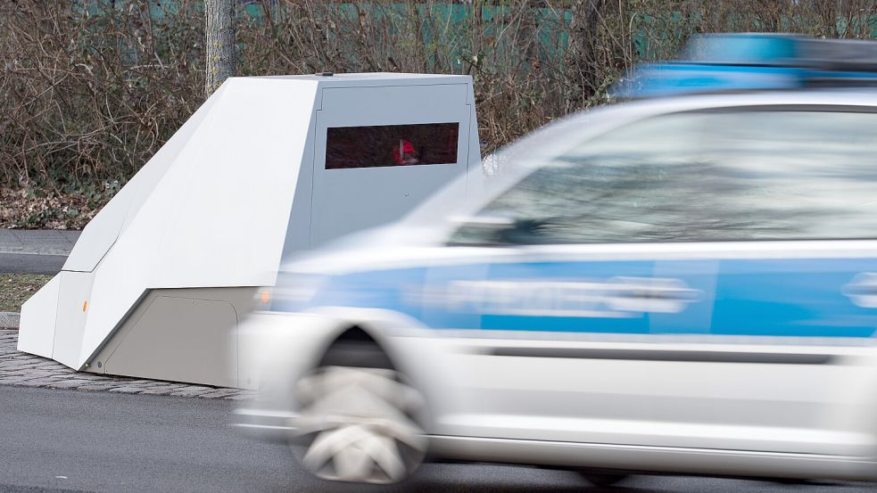 Ein Polizeiwagen fährt an einem mobilen Blitzer vorbei. Foto: Bernd von Jutrczenka/dpa