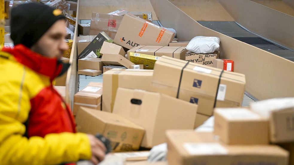 Ein DHL-Paketbote ist in einer Zustellbasis mit einer Vielzahl an Paketen beschäftigt. Der Logistikkonzern hat Jahreszahlen für 2025 vorgelegt, er hat profitablere Geschäfte gemacht als zuvor. Foto: Wolf von Dewitz/dpa