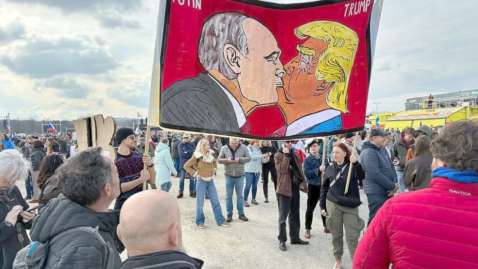 Demonstranten halten bei einer Kundgebung des Bündnisses „Eine Million Augenblicke für Demokratie“ ein Banner, auf dem sich stilisiert US-Präsident Trump und Russlands Präsident Putin küssen. Foto: Michael Heitmann/dpa