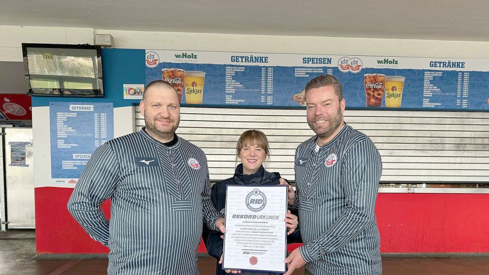 Das Catering-Team des Ostseestadions Rostock um Geschäftsführer Christoph Wulff (r) und Küchenchef Jens Schaumburg (l) hat das längste Fischbrötchen der Welt produziert. Bestätigt wurde der Rekord von Laura Koblischek (M) vom Rekord-Institut Deutschland. (Foto Handout) Foto: --/F.C. Hansa Rostock /dpa