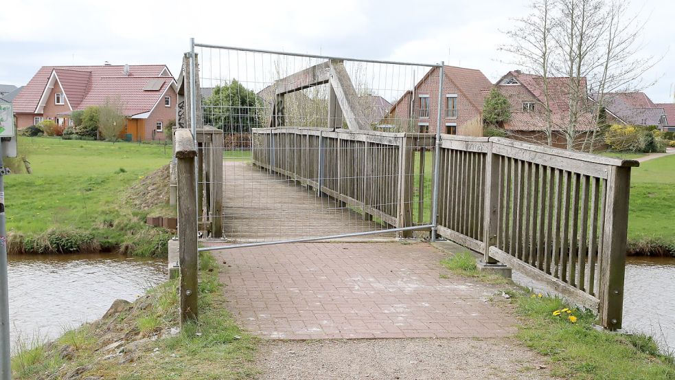Mit Absperrgitter gesichert: Die marode Fuß- und Radfahrerbrücke über die Sagter Ems in Ramsloh ist seit einer Prüfung im April 2025 gesperrt. Der Neubau soll im dritten Quartal 2026 starten. Foto: Hans Passmann